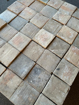 A square French reclaimed terra cotta tile in a variety of gray colors creates a lovely powder room floor.